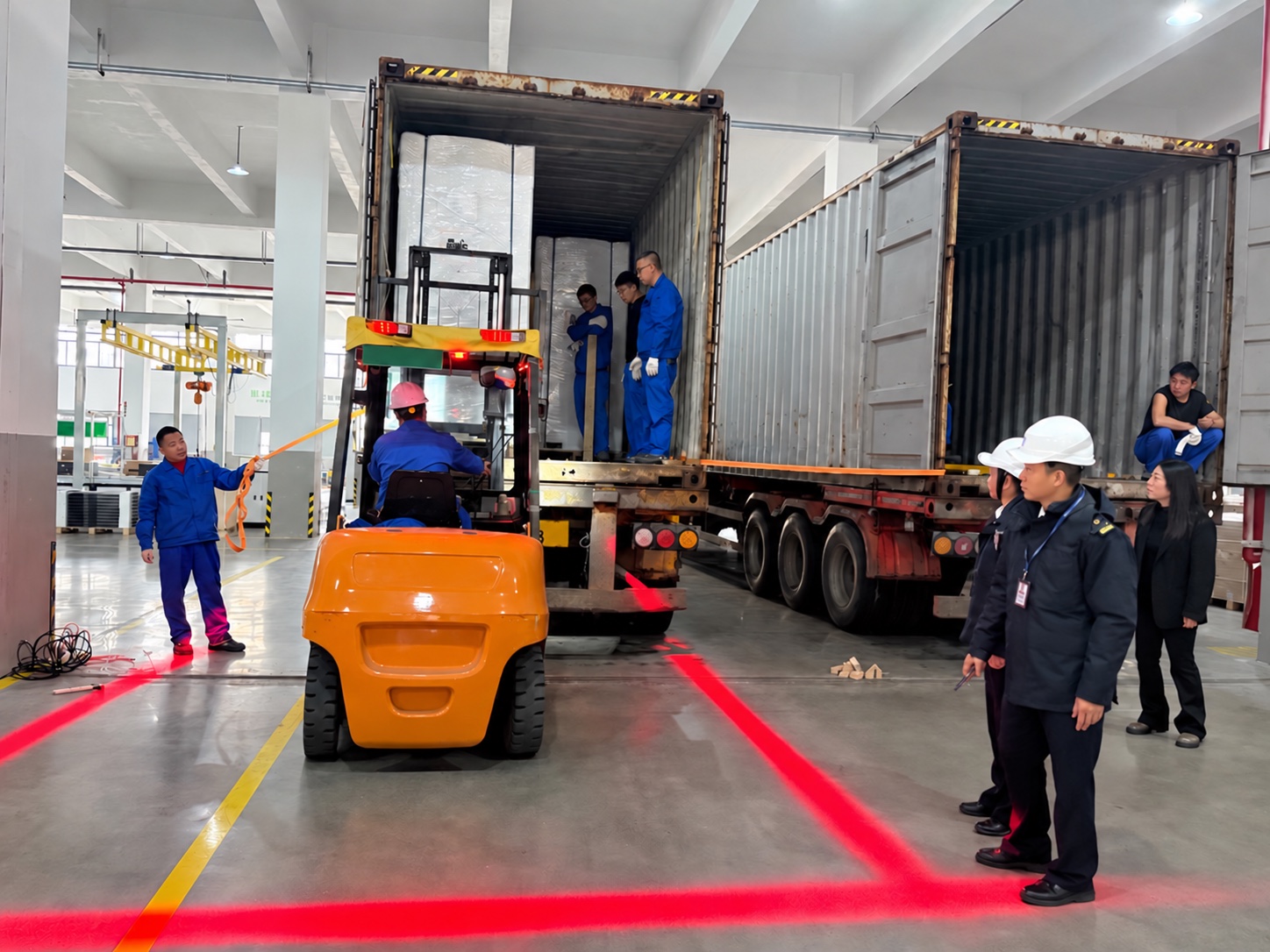 Forklift loading packaged industrial equipment into shipping containers at a supplier loading bay