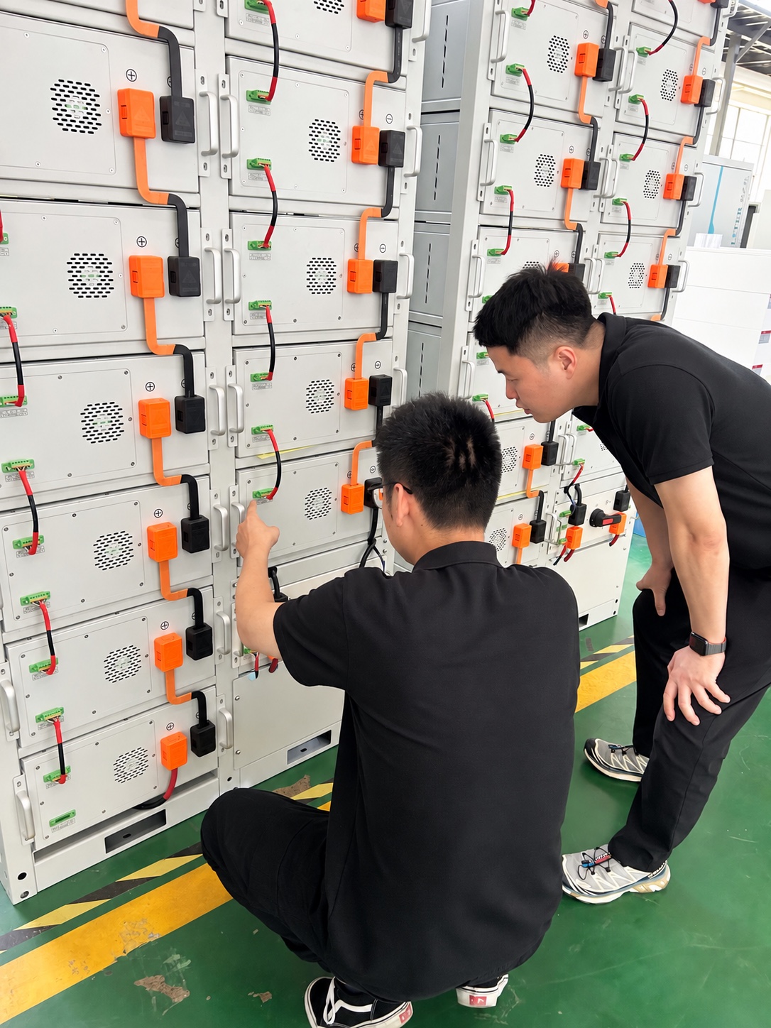 Technicians reviewing battery-module wiring during supplier assembly