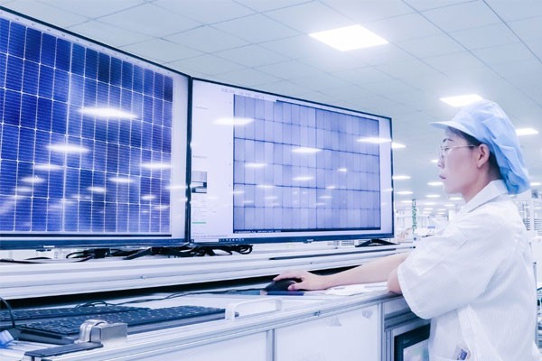 Operator reviewing solar-module EL and visual inspection images on two screens at a supplier production line